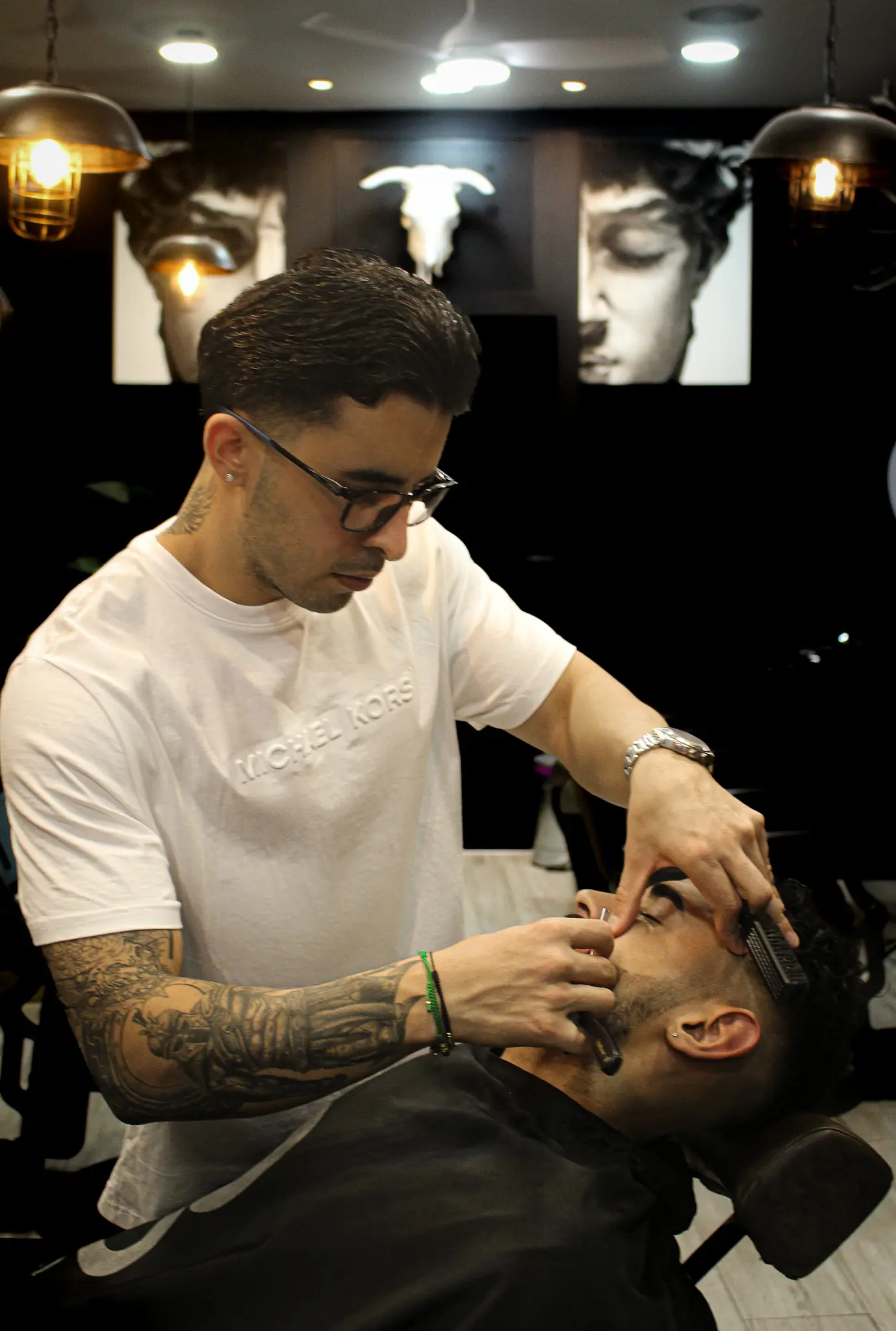 Eliud perfilando a navaja a un cliente en la silla